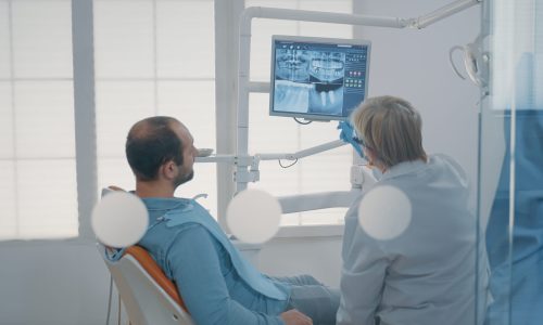 Mature dentist pointing at teeth radiography on monitor Mature dentist pointing at teeth radiography on monitor